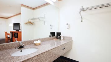 Ett hotellbadrum med ett handfat i granit, en spegel, en handduksställning, en hårtork och en kaffebryggare.