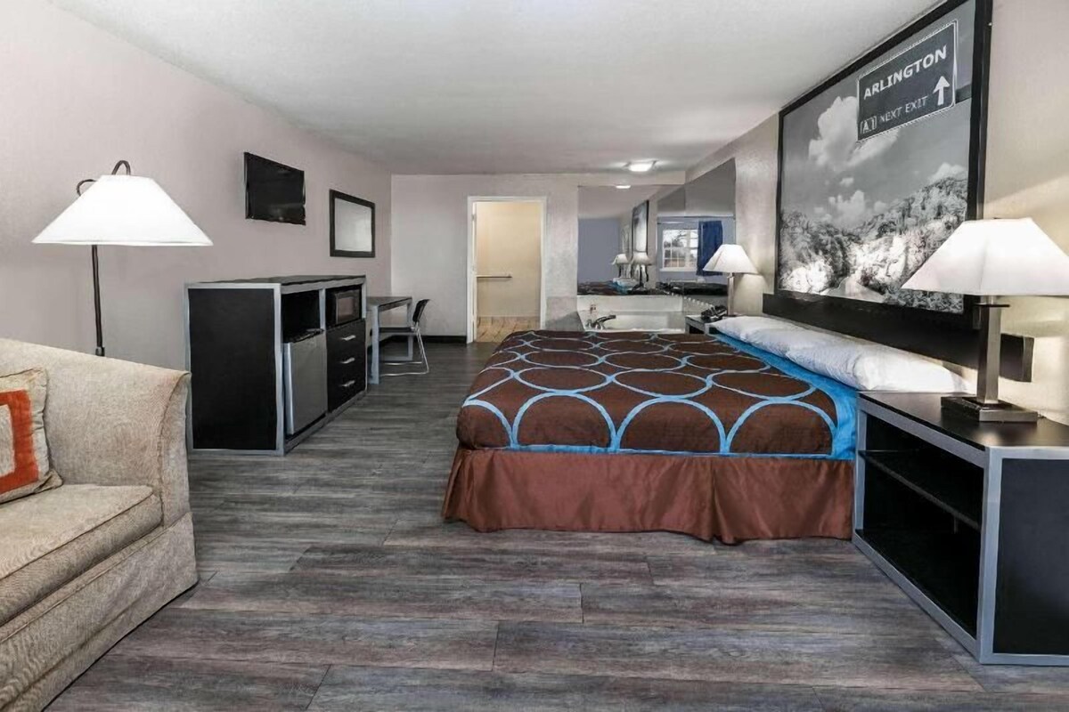 A hotel room with a bed, desk, chair, and a TV on the wall.