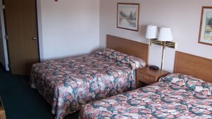 Una habitación de hotel con dos camas, una mesita de noche, una lámpara y una puerta.