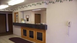 Un área de recepción con mostrador de madera, una mesa de recepción, un teléfono de recepción y piso de baldosas.