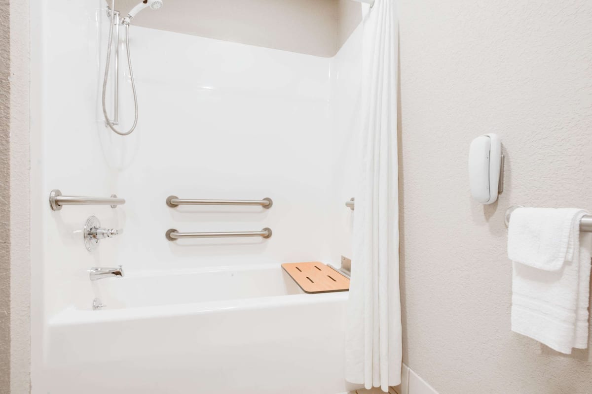 A white bathtub with a showerhead, grab bars, and a towel rack.