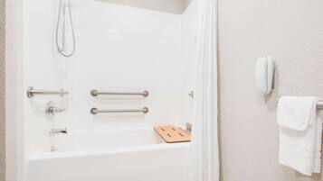 Una bañera blanca con ducha, barras de apoyo y un perchero.