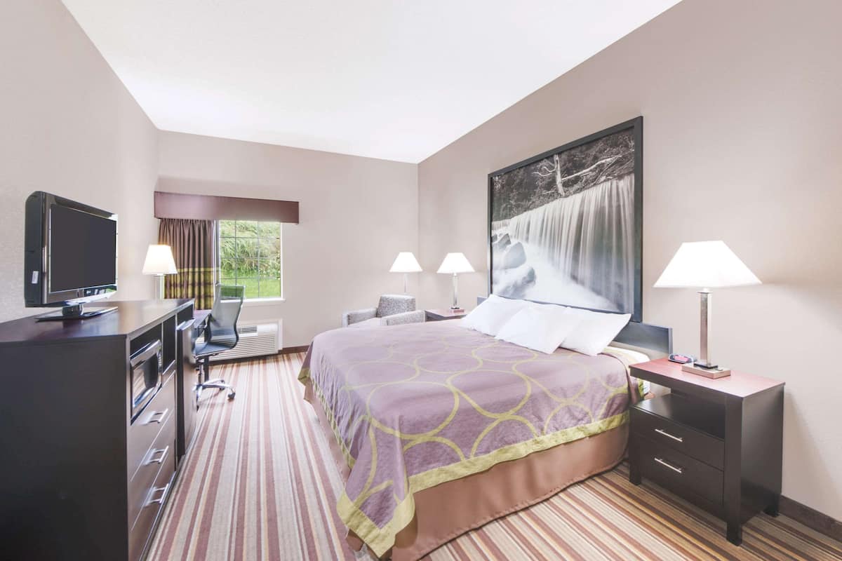 A hotel room with a bed, desk, TV, and two lamps.