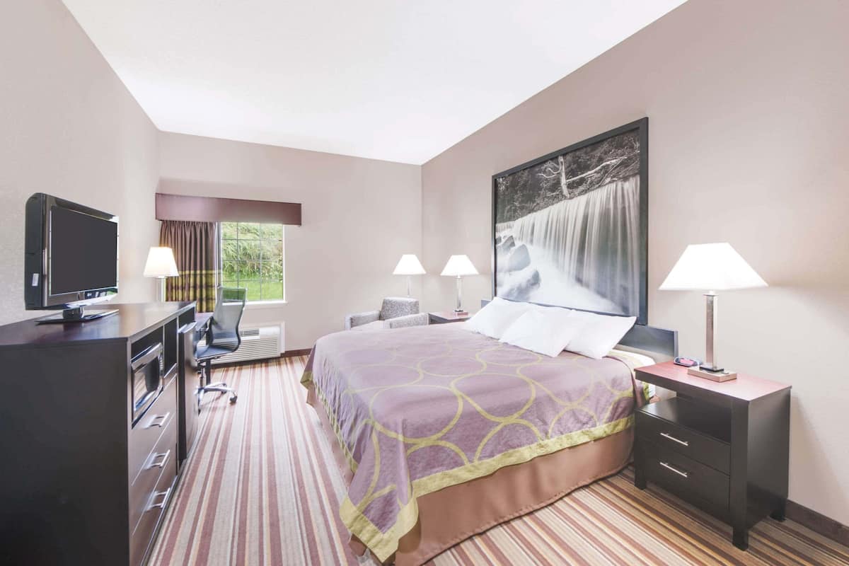 A hotel room with a bed, desk, TV, and two lamps.