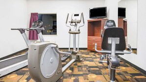A gym with an exercise bike, elliptical, and a stationary bike.