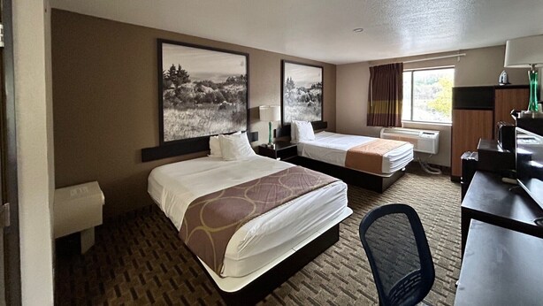 A hotel room with two beds, a desk, a chair, a window with curtains, and two wall-mounted paintings. - Super 8 by Wyndham Lynchburg VA (Lynchburg)