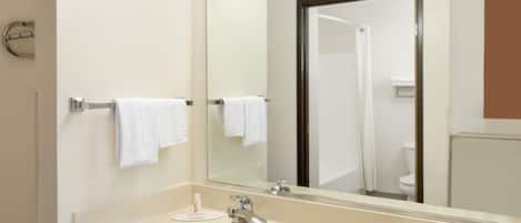 A bathroom with a beige sink, a mirror, and two towels hanging on towel bars.
