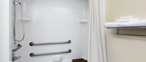 Un baño moderno con bañera, ducha y barras de apoyo.