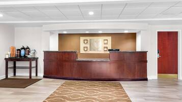 A reception area with a wooden reception desk, a wall-mounted artwork, and a door to the right.