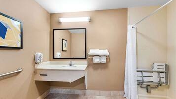 Baño con lavamanos, espejo, toallero, ducha y barras de apoyo.