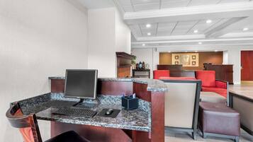 A reception area with a computer desk, a chair, and a seating area with red cushions.