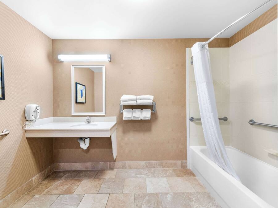 A bathroom with a sink, mirror, towel rack, and shower.