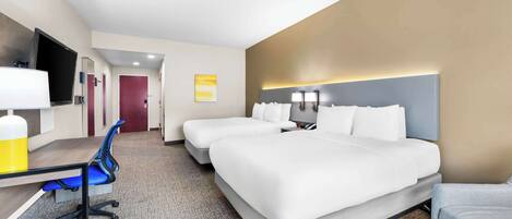 A hotel room with a large bed, a desk with a chair, a TV, and a bathroom door.