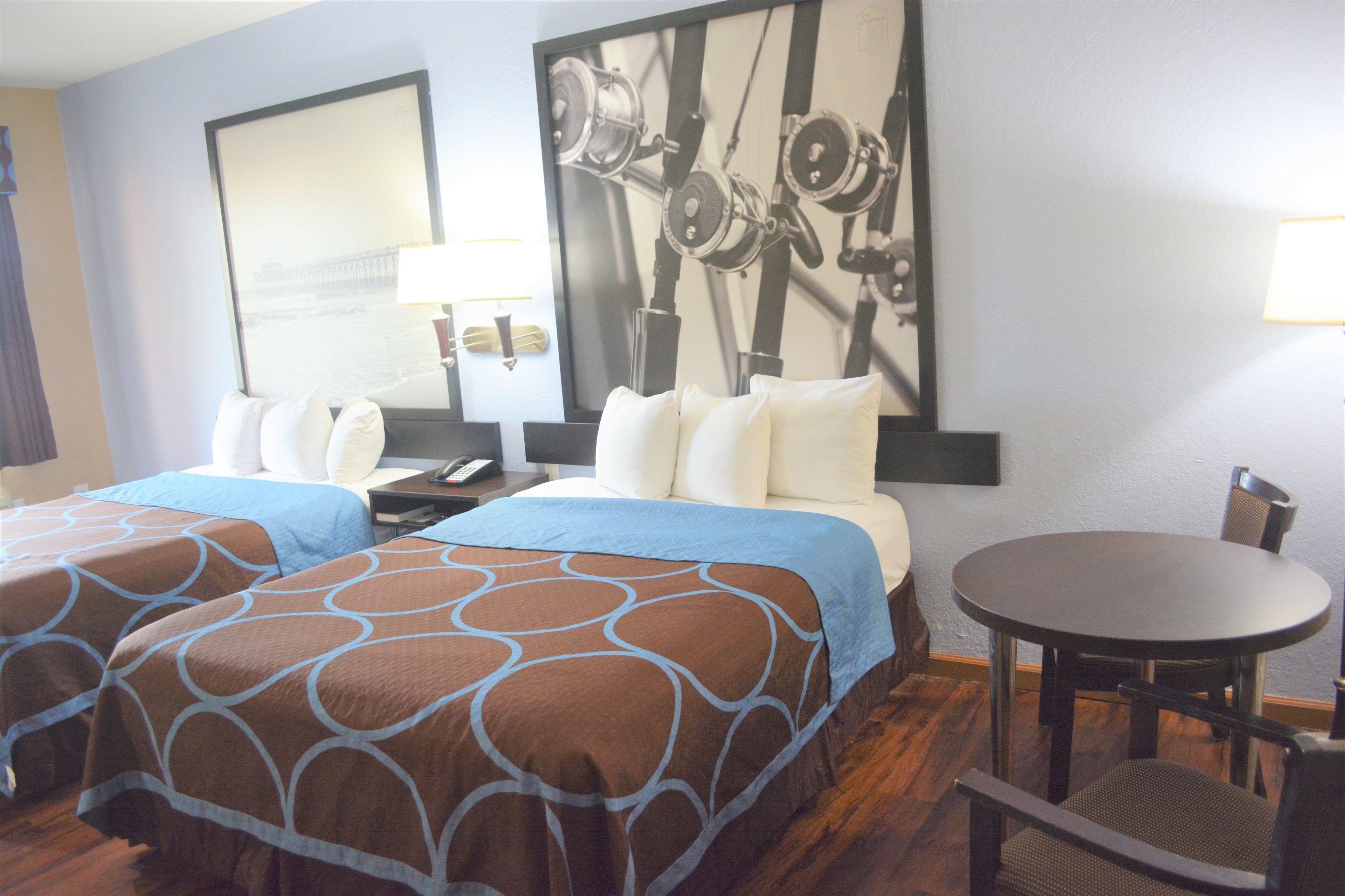 A hotel room with two beds, a round table, and a chair.