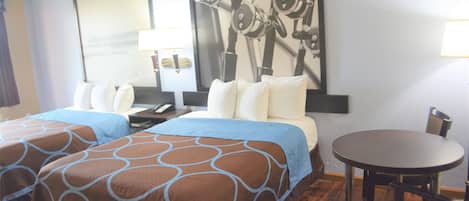 A hotel room with two beds, a round table, and a chair.