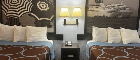 A hotel room with two beds, a nightstand, a lamp, and a large poster of a cruise ship.
