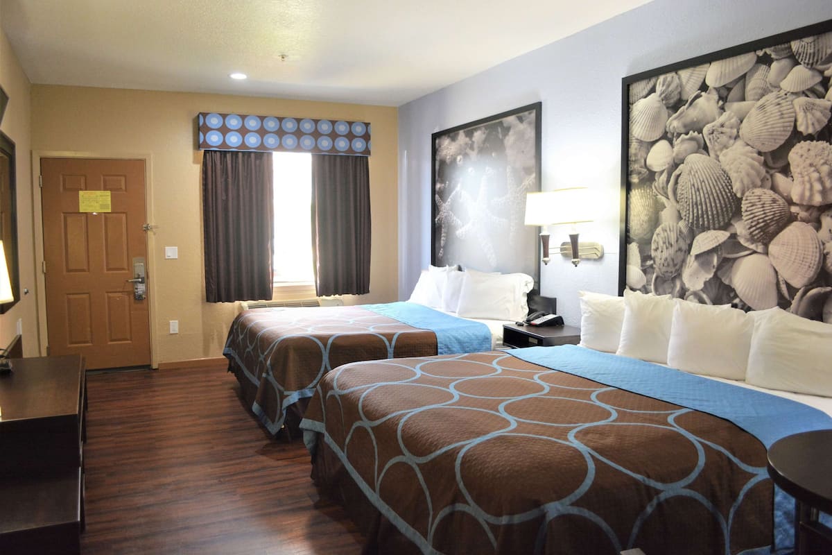 Ein Hotelzimmer mit zwei Betten, einem Nachttisch, einem Schreibtisch und einer großen Wandkunst in Form einer Meeresschnecke.