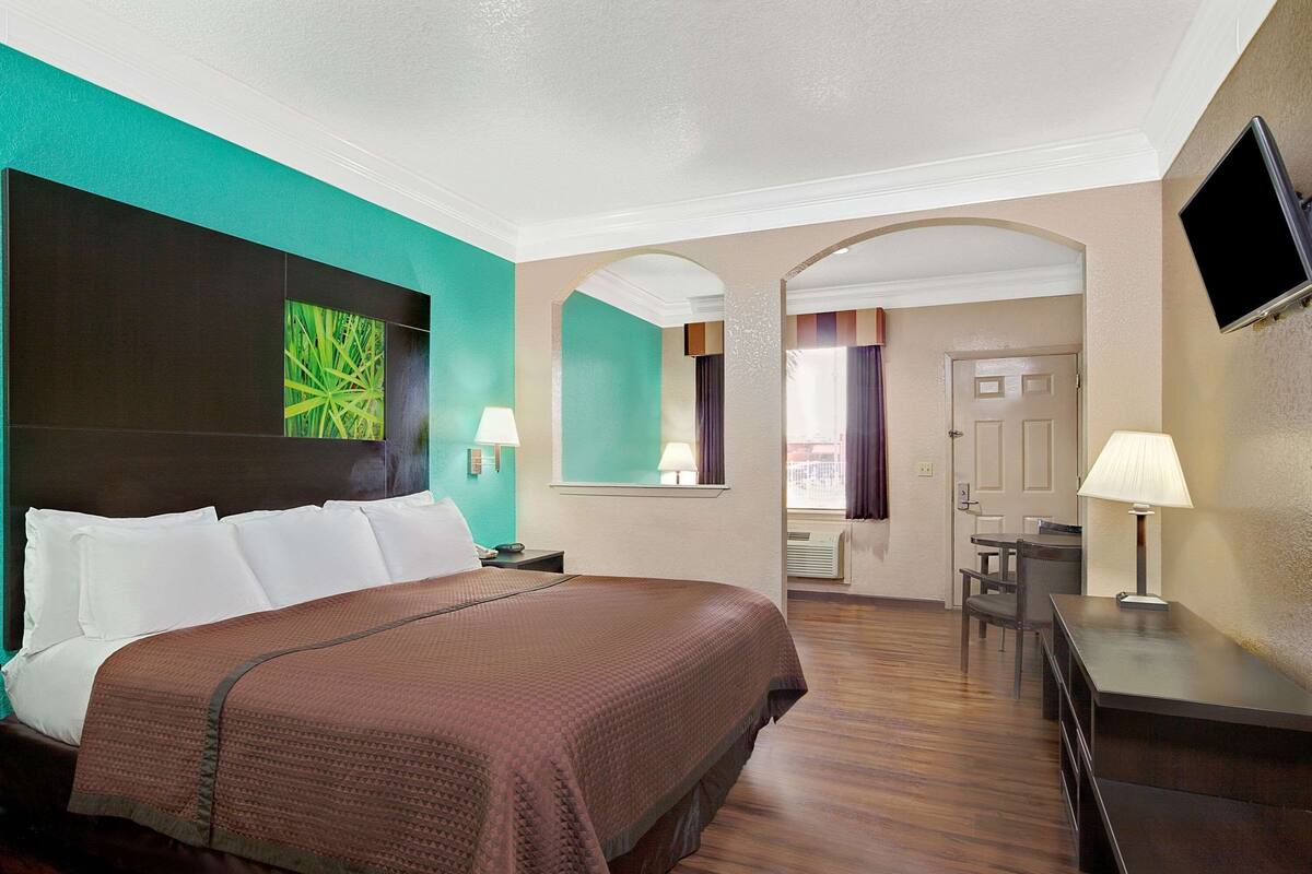 Ein Hotelzimmer mit Bett, Schreibtisch und Fernseher.