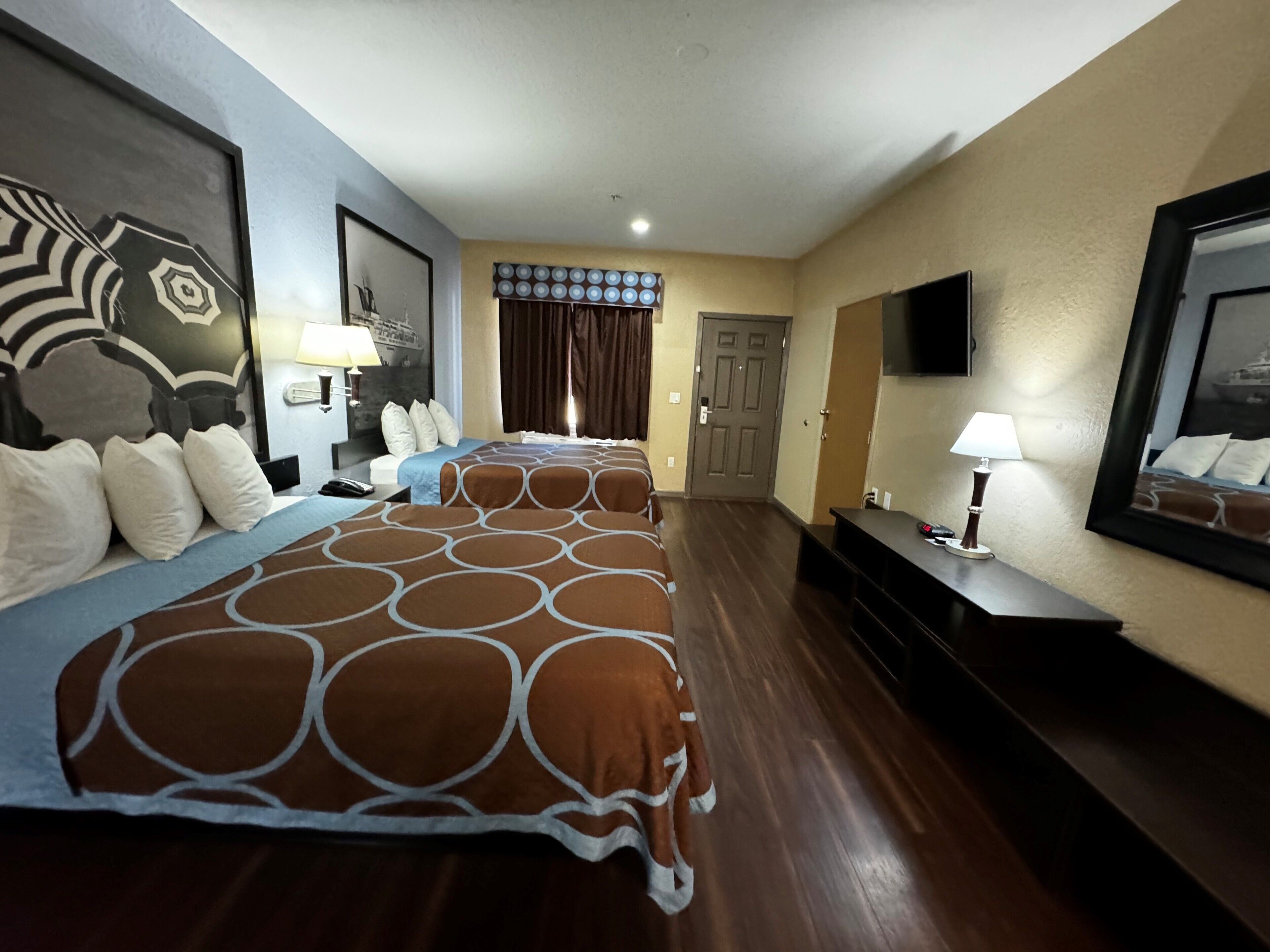 Habitació d'hotel amb dos llits, una televisió, un escriptori i una porta.