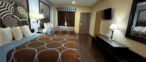 A hotel room with two beds, a TV, a desk, and a door.