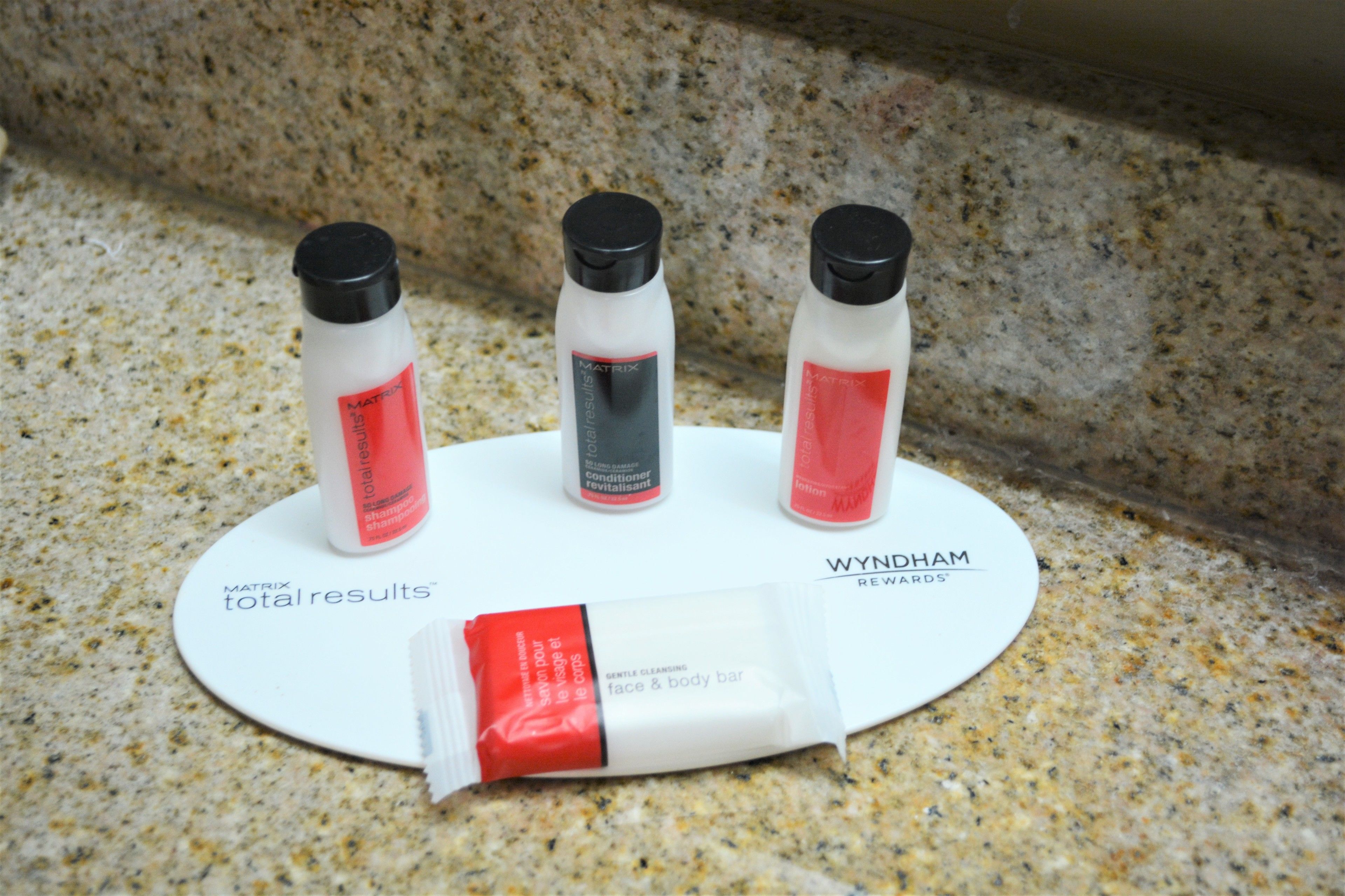 A countertop with three bottles of Matrix Total Results body wash and a bar of Wynnham Rewards face and body bar soap.