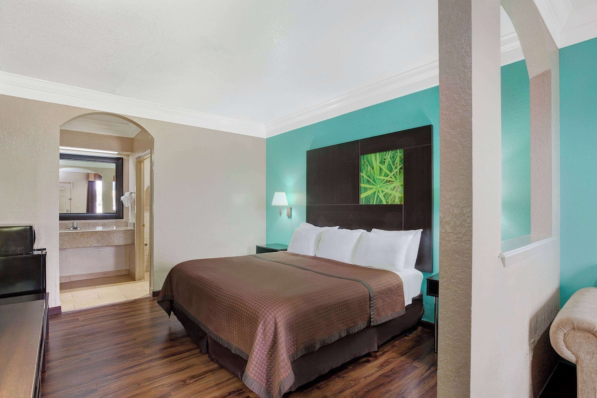 Ein Hotelzimmer mit Bett, Schreibtisch, Spiegel und Blick auf einen Flur.