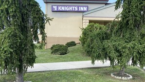 En byggnad som tillhör hotellkedjan Knights Inn, med en skylt, omgiven av välskött gräsmatta och träd.