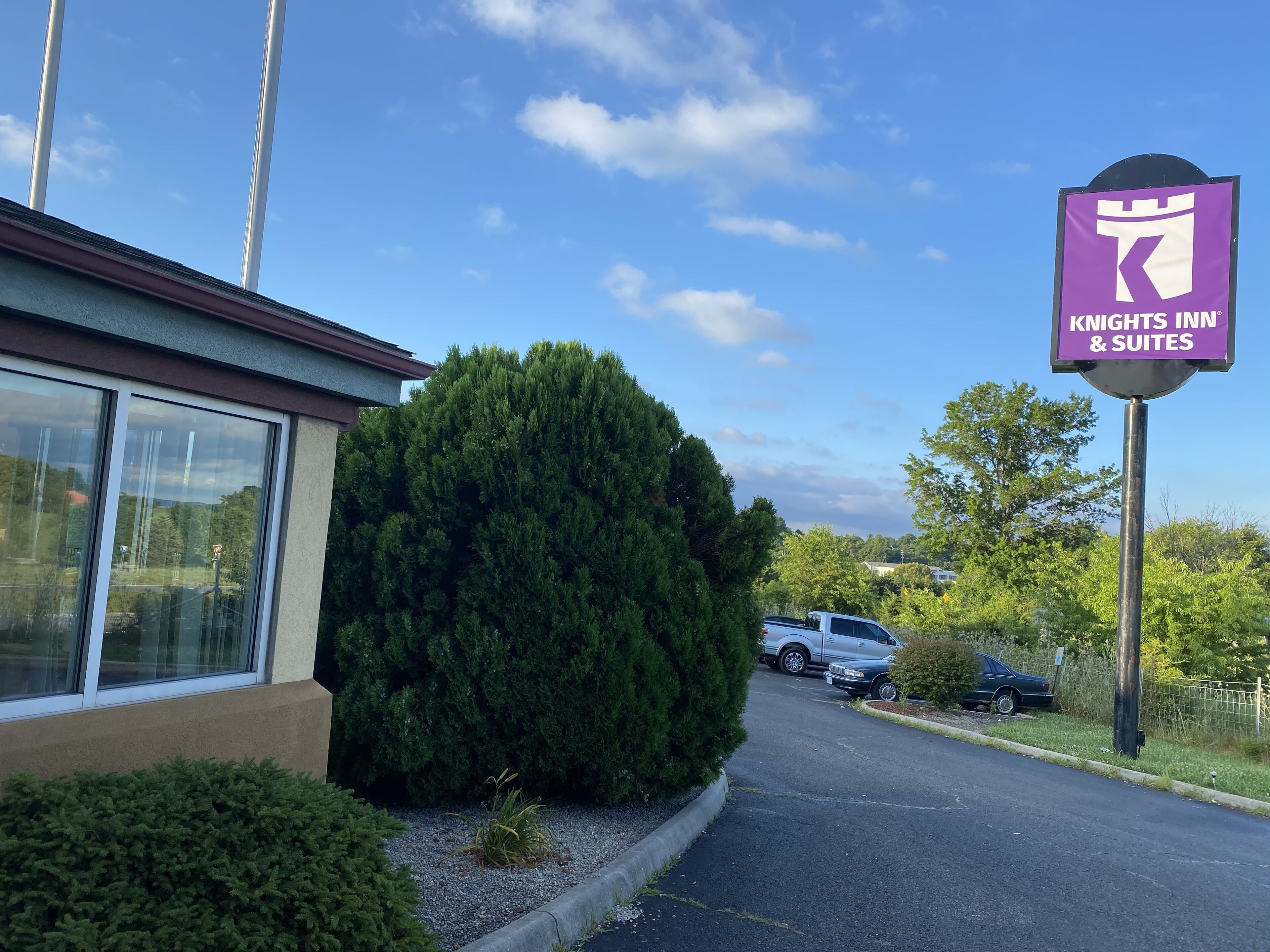 A Knights Inn & Suites sign, a parking lot, and a building with large windows.