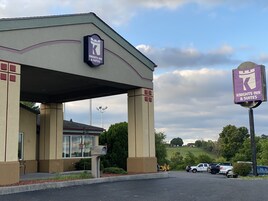 Edificio de Knights Inn & Suites con entrada cubierta, buzón y estacionamiento con varios autos.