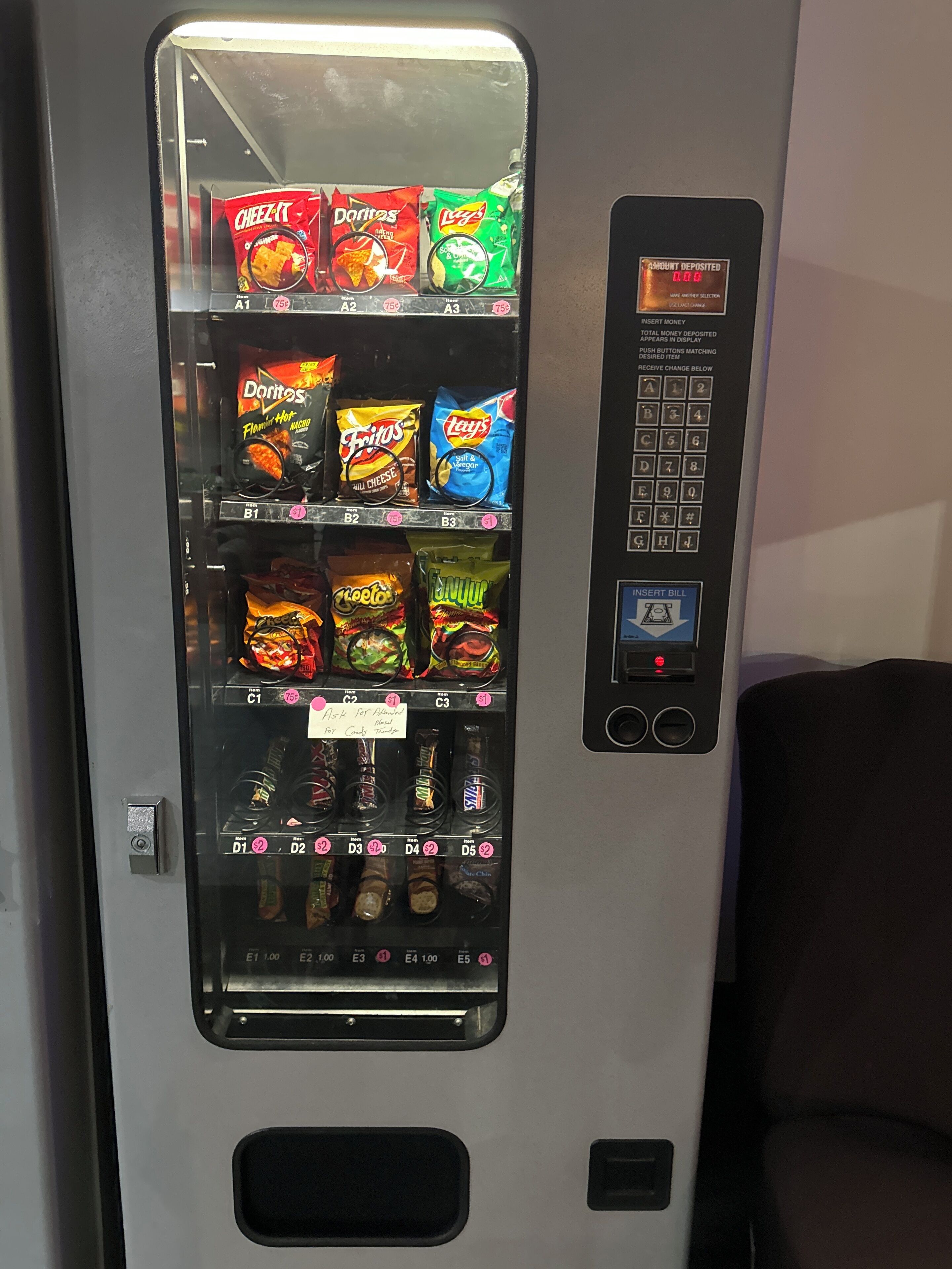 Máquina de vendas com diversas opções de lanches, incluindo batatas fritas, cachorros-quentes e doces.