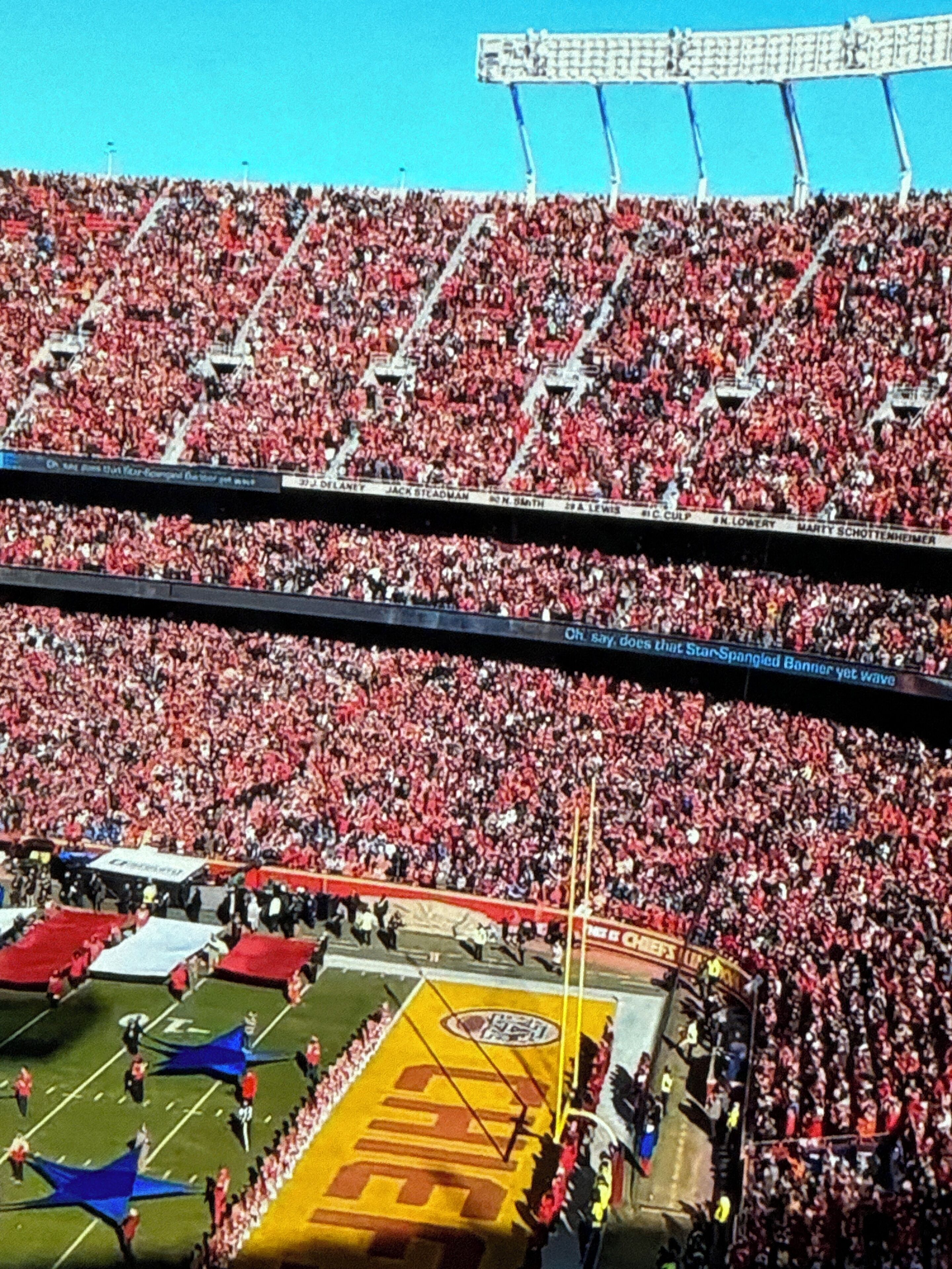 A stadium filled with spectators, featuring tiered seating and a large field.