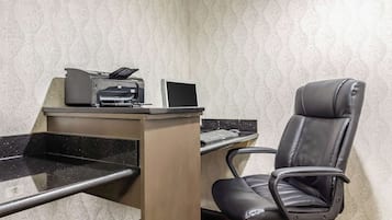 Un espace de travail équipé d’une imprimante, d’un ordinateur portable et d’un fauteuil en cuir noir.