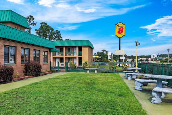 A motel with a green roof, a sign for 'Super 8 by Wyndham', and outdoor seating.