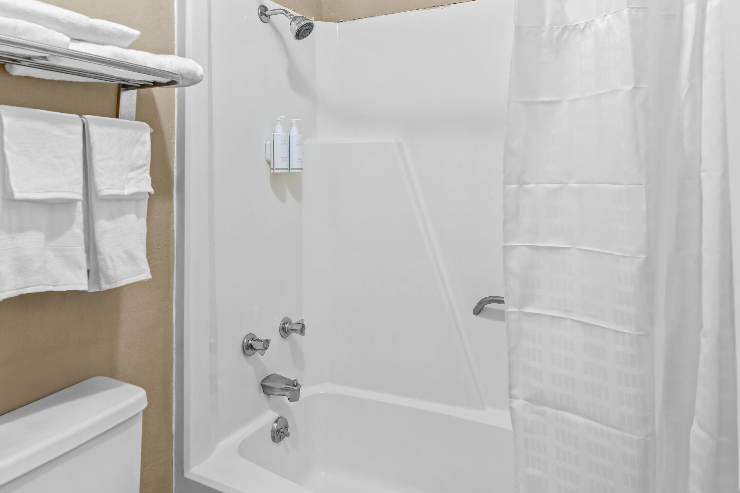 A modern bathroom with a bathtub, a toilet, and a towel rack with folded towels.