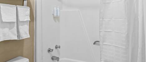 A modern bathroom with a bathtub, a toilet, and a towel rack with folded towels.