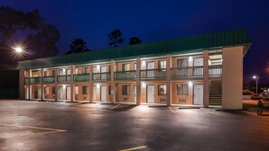 Un motel de varios pisos con techo verde, múltiples balcones y un estacionamiento.