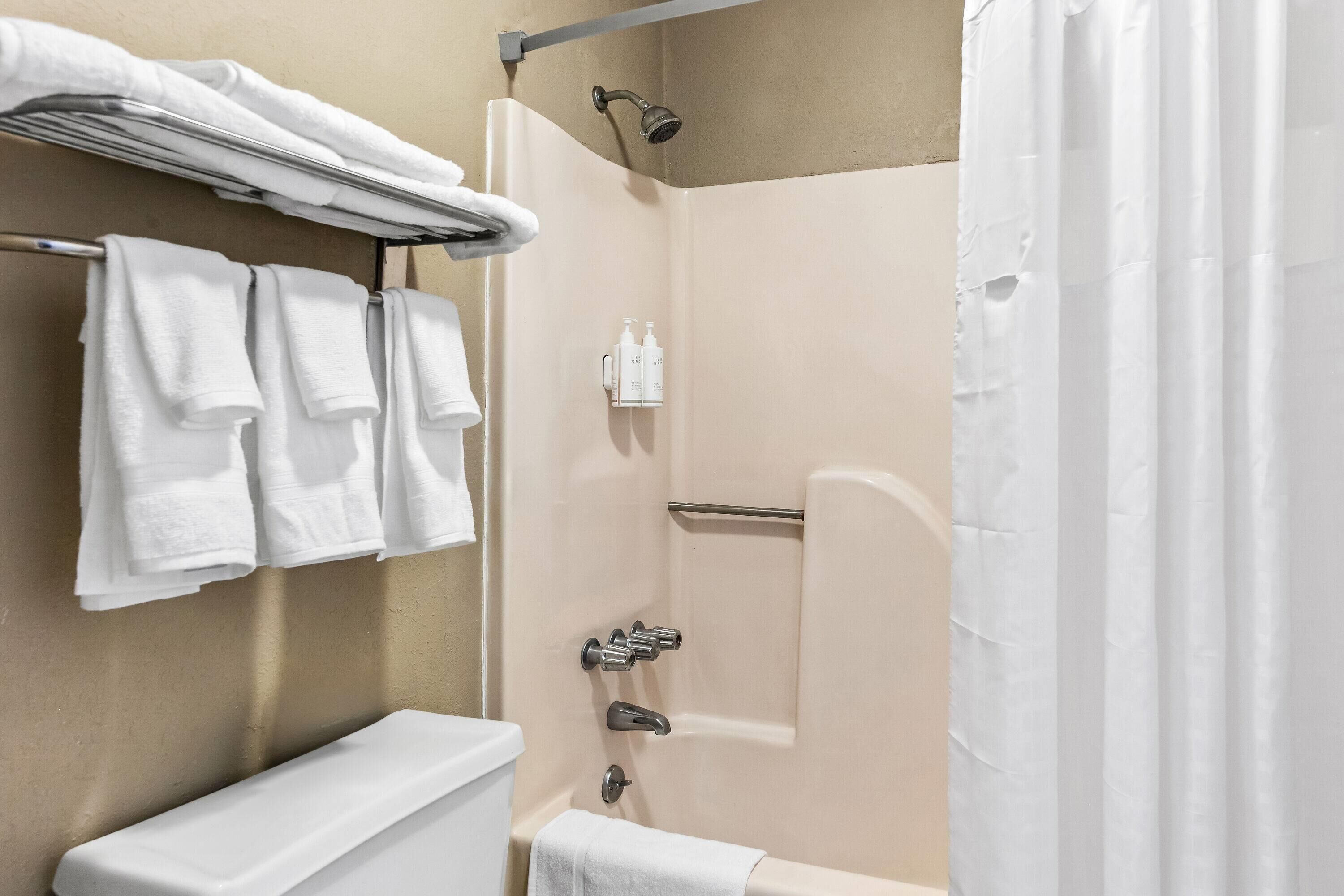 A bathroom with a toilet, a shower with a glass door, and a towel rack with multiple towels.