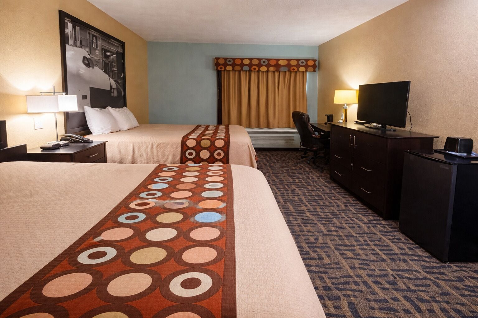 Une chambre d’hôtel avec deux lits, un bureau, une télévision et une chaise.