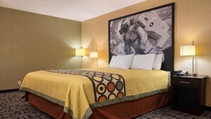 Une chambre d’hôtel avec un lit, deux lampes de chevet, une table de chevet avec un téléphone et un grand tableau encadré au mur.