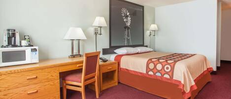 Habitación de hotel con cama, escritorio, silla y microondas.