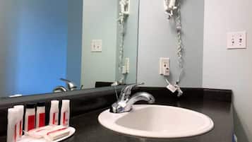 A bathroom with a white sink, a mirror, and a hairdryer mounted on the wall.
