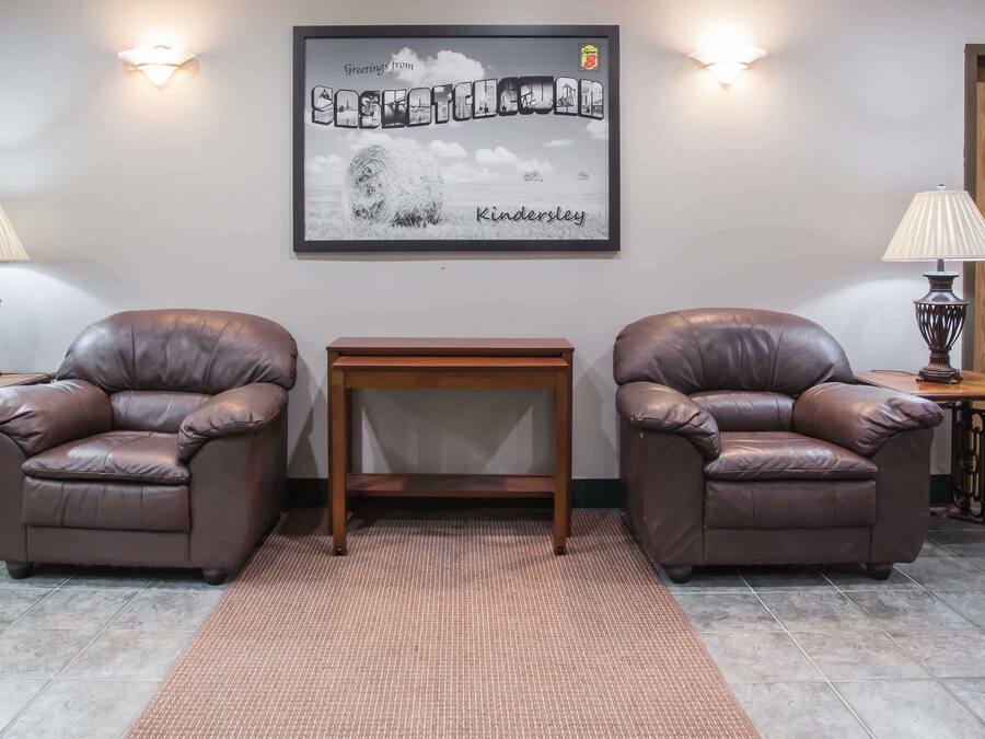 Una habitación con dos sillones de cuero, una mesita de madera y un cuadro enmarcado en la pared.