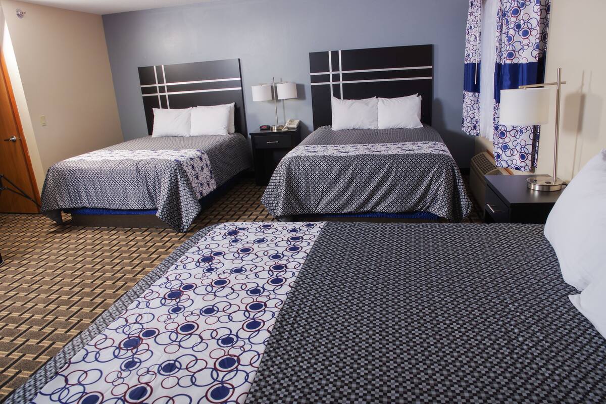 A hotel room with two single beds, a desk, a chair, a lamp, and a telephone.