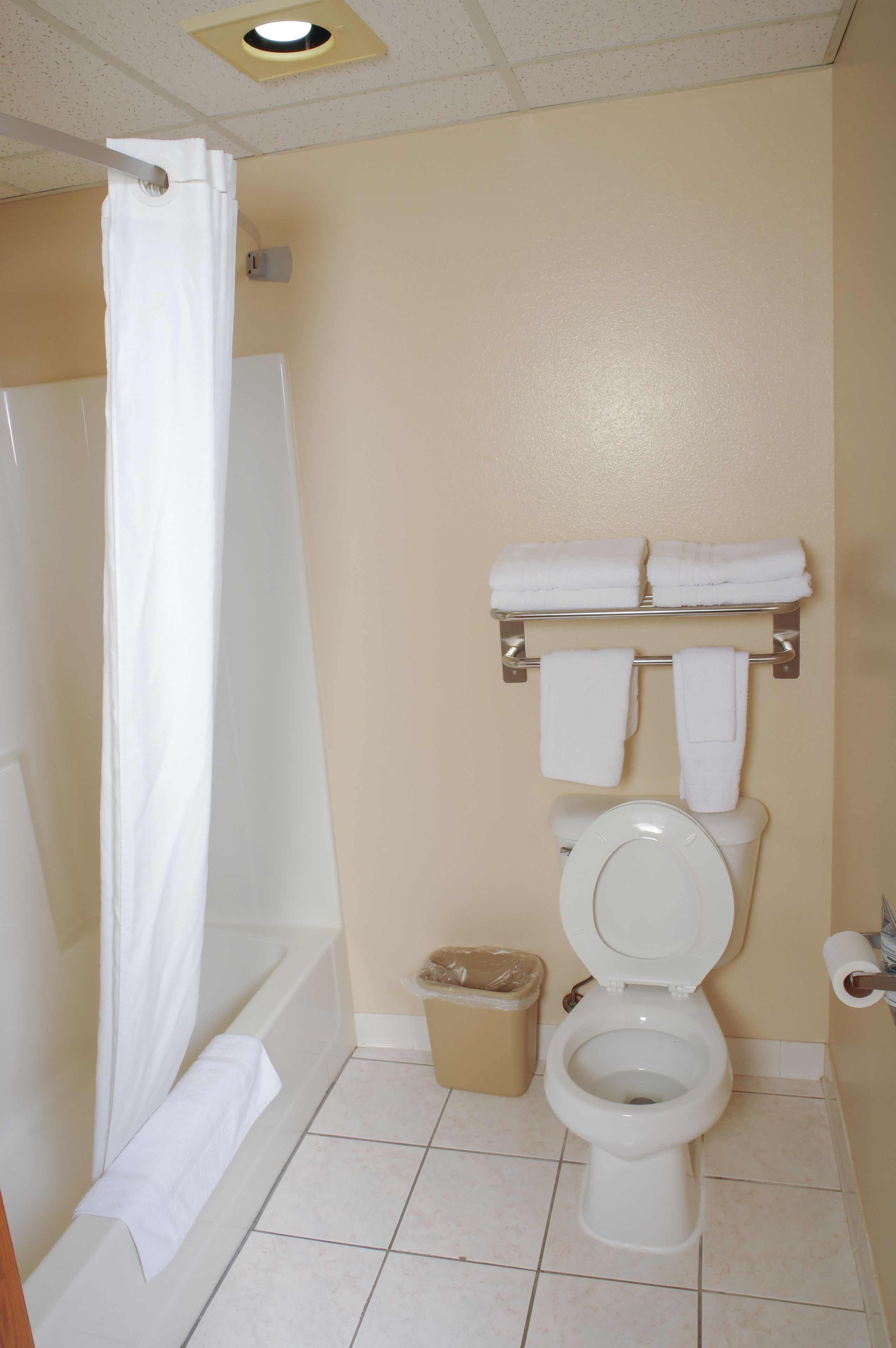 A bathroom with a bathtub, toilet, and a towel rack with towels.