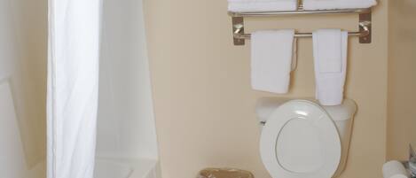 Un baño con bañera, inodoro y toallero con toallas.