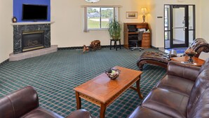 A lobby with a fireplace, leather seating, a television, and a large window. - Americas Best Value Inn & Suites Spring Valley (Spring Valley)