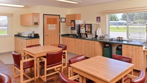 A breakfast room with wooden tables and chairs, a coffee machine, and a view of the outdoors. - Americas Best Value Inn & Suites Spring Valley (Spring Valley)