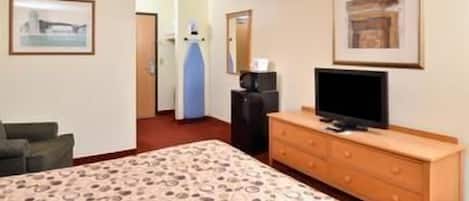 A hotel room with a bed, a television on a wooden dresser, a desk, and a chair.