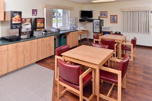 A restaurant with a counter, seating area, and a television.
