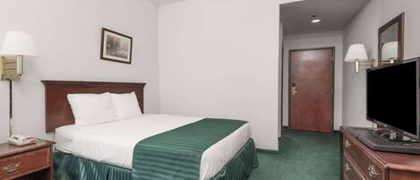 Una habitación de hotel con cama, cómoda, televisor y una puerta que da a otra habitación.
